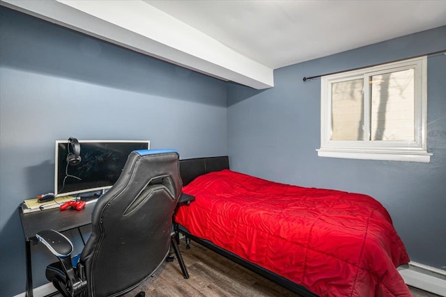 bedroom featuring wood-type flooring and a baseboard heating unit