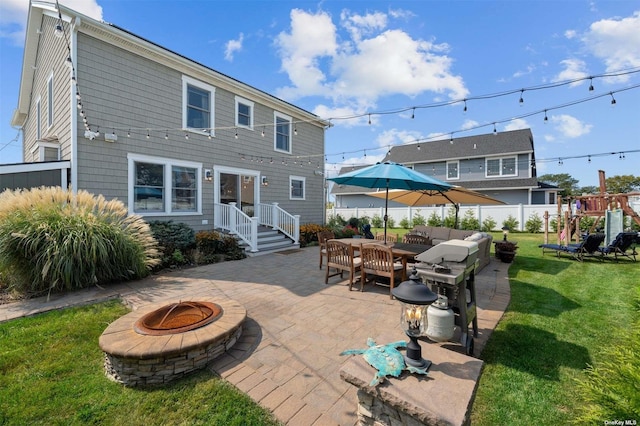 rear view of house with a yard, a playground, a patio area, and an outdoor living space with a fire pit