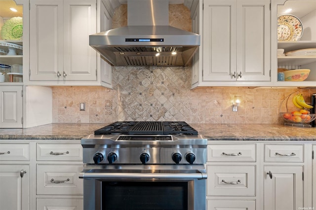 kitchen with stainless steel stove, ventilation hood, light stone countertops, and white cabinets