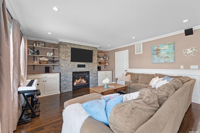 living room featuring dark wood-type flooring, a stone fireplace, and crown molding