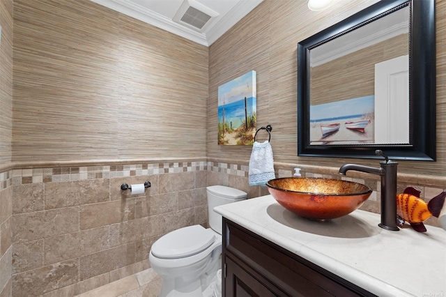 bathroom with tile walls, vanity, crown molding, and toilet