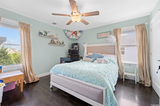 bedroom with multiple windows, dark hardwood / wood-style floors, and ceiling fan