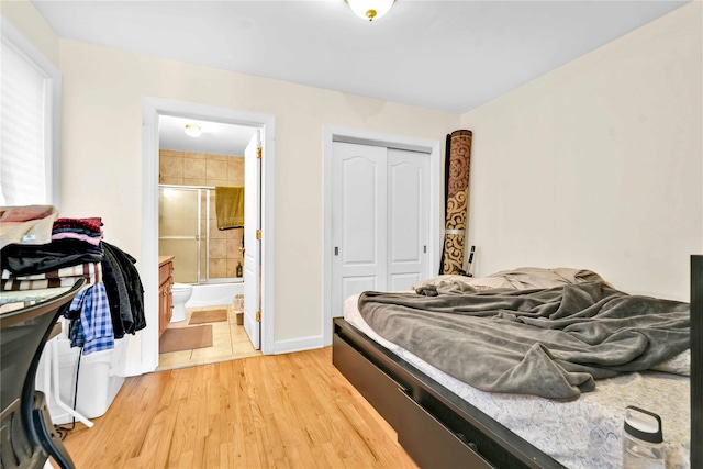 bedroom with ensuite bath, wood-type flooring, and a closet