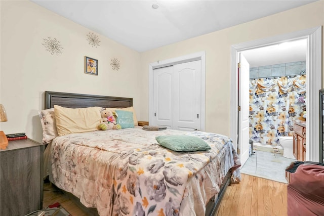 bedroom with hardwood / wood-style flooring, connected bathroom, and a closet