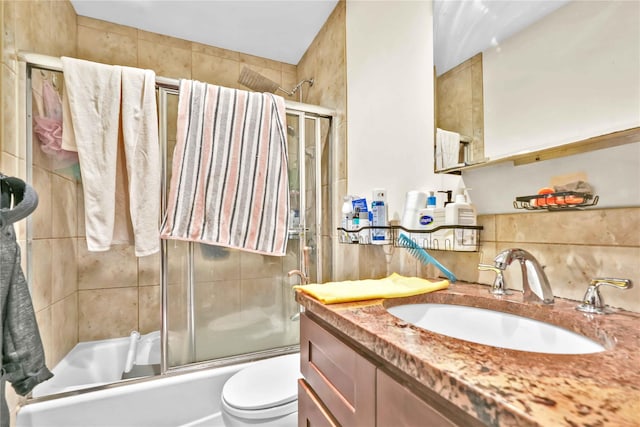 full bathroom featuring vanity, toilet, combined bath / shower with glass door, and decorative backsplash