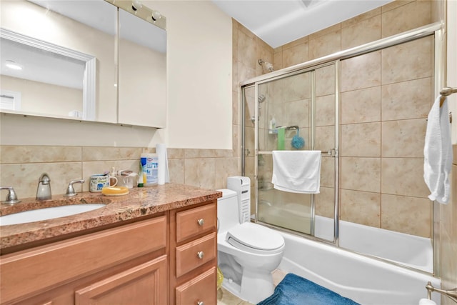 full bathroom with shower / bath combination with glass door, tile walls, vanity, decorative backsplash, and toilet