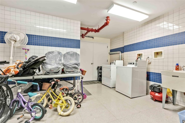 laundry room with sink, washer and dryer, and tile walls