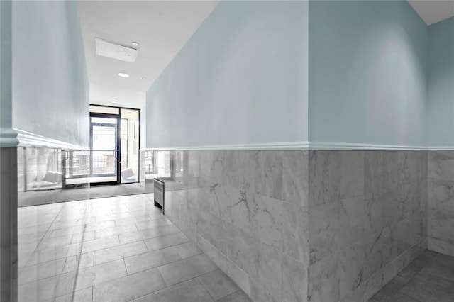 hallway featuring tile walls and light tile patterned floors