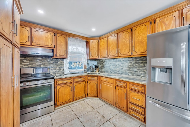 kitchen with light tile patterned floors, decorative backsplash, light stone countertops, and appliances with stainless steel finishes