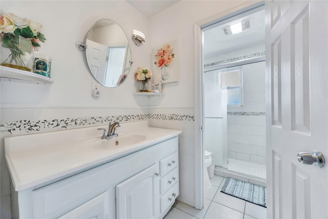 bathroom with tile walls, tile patterned flooring, vanity, tiled shower, and toilet