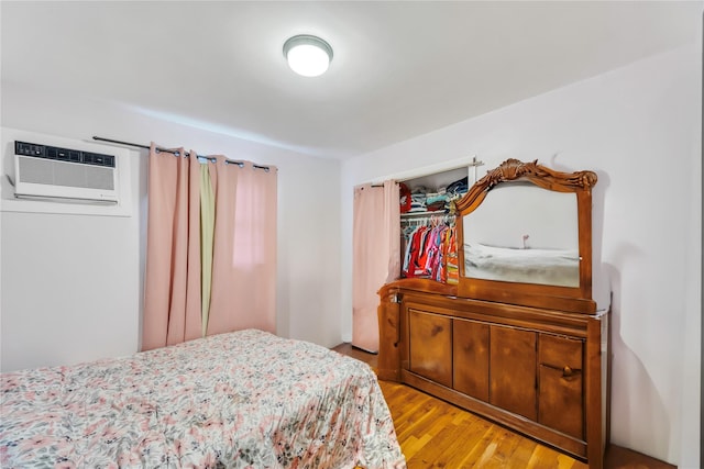 bedroom with a wall mounted air conditioner and light hardwood / wood-style flooring