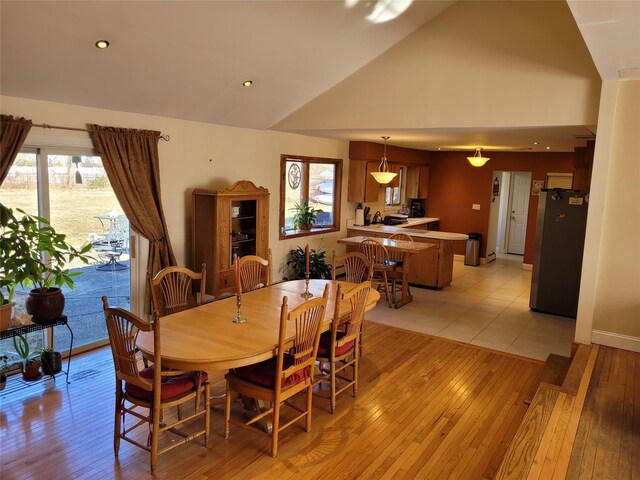 dining space with high vaulted ceiling, a healthy amount of sunlight, and light hardwood / wood-style floors