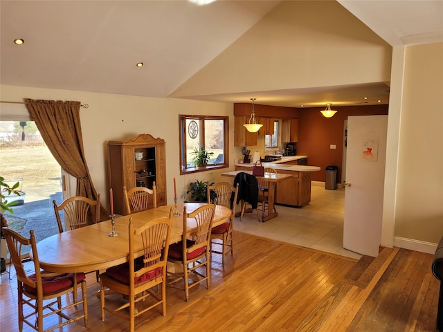 dining room with high vaulted ceiling and light wood-type flooring