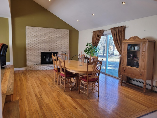 dining area featuring a fireplace, light hardwood / wood-style floors, and vaulted ceiling