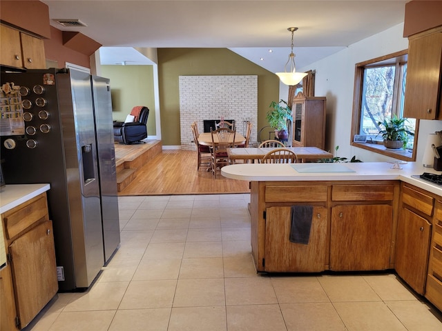 kitchen with stainless steel fridge with ice dispenser, lofted ceiling, hanging light fixtures, light tile patterned floors, and kitchen peninsula