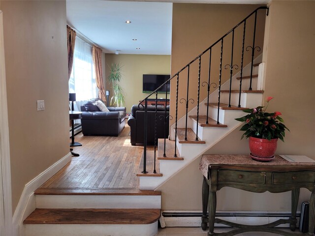 staircase with hardwood / wood-style flooring and baseboard heating