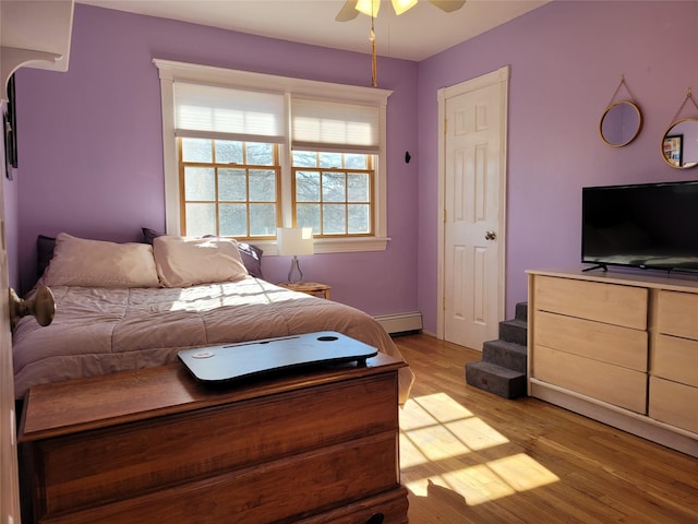 bedroom with baseboard heating, ceiling fan, and light hardwood / wood-style floors