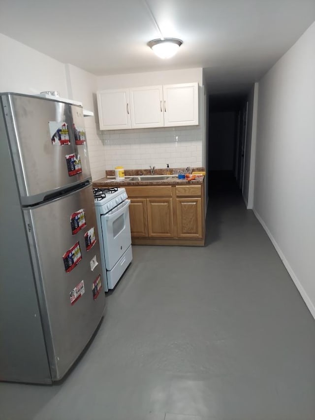 kitchen featuring tasteful backsplash, sink, white cabinets, stainless steel fridge, and white gas range oven