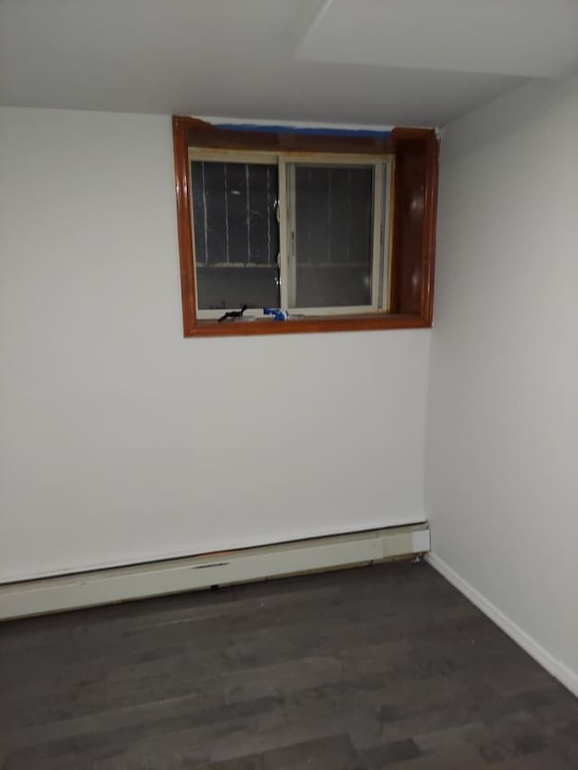 empty room featuring baseboard heating and dark hardwood / wood-style flooring