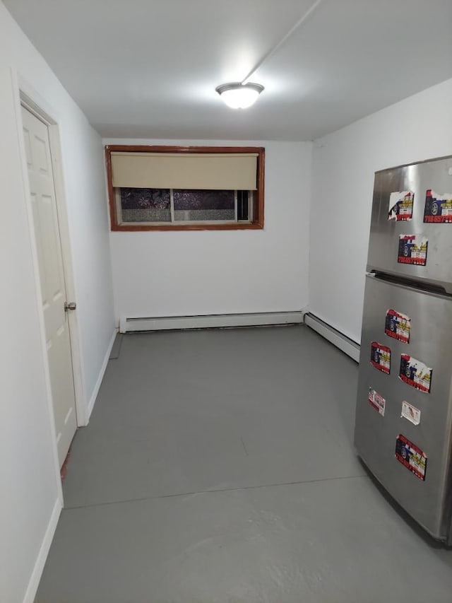 basement with a baseboard heating unit and stainless steel fridge