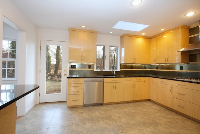 kitchen with appliances with stainless steel finishes, light brown cabinetry, a skylight, sink, and backsplash