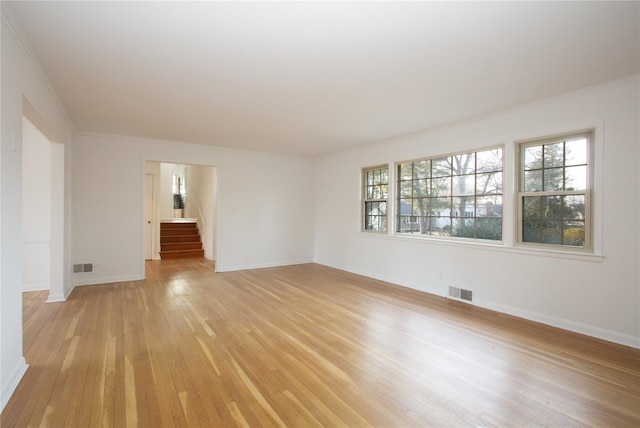 empty room with crown molding and light hardwood / wood-style flooring