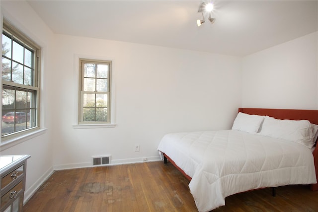 bedroom with dark hardwood / wood-style floors and multiple windows