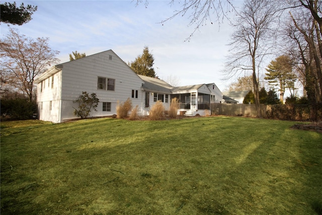 rear view of house with a yard and a sunroom