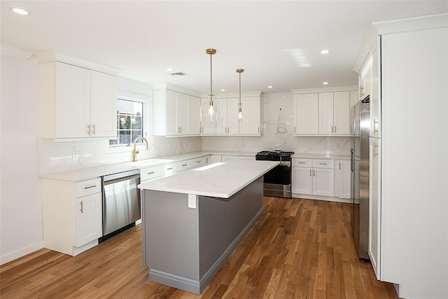 kitchen featuring sink, hanging light fixtures, appliances with stainless steel finishes, a kitchen island, and white cabinets