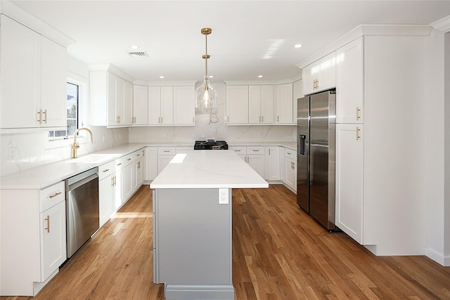 kitchen with stainless steel appliances, a center island, pendant lighting, and white cabinets