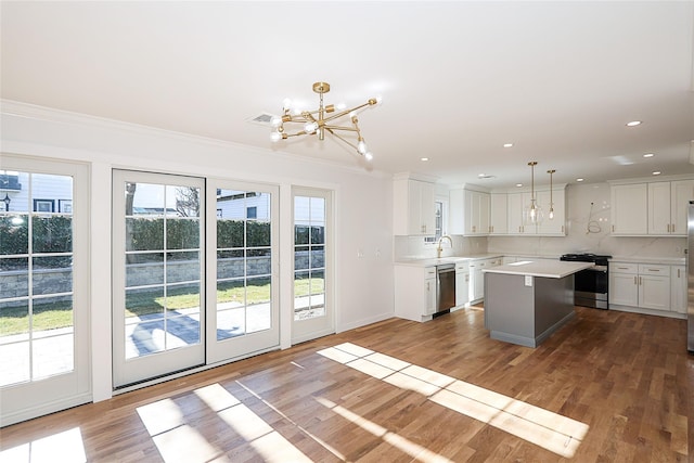 kitchen with sink, appliances with stainless steel finishes, white cabinetry, hanging light fixtures, and a center island