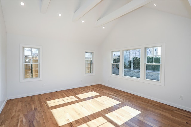 unfurnished room featuring beamed ceiling, hardwood / wood-style flooring, a healthy amount of sunlight, and high vaulted ceiling