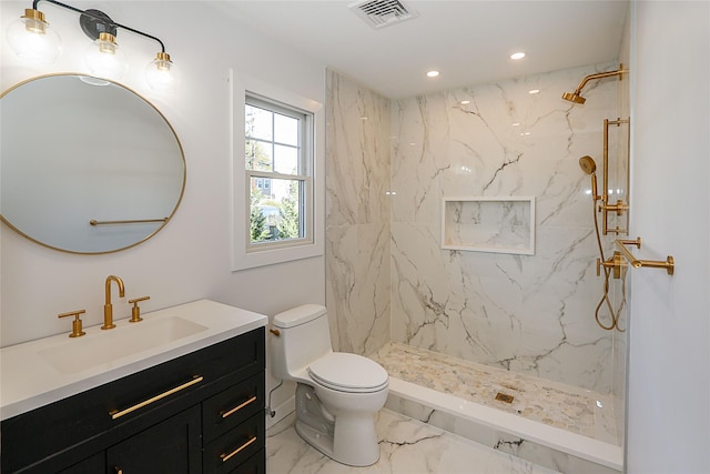 bathroom featuring vanity, a tile shower, and toilet