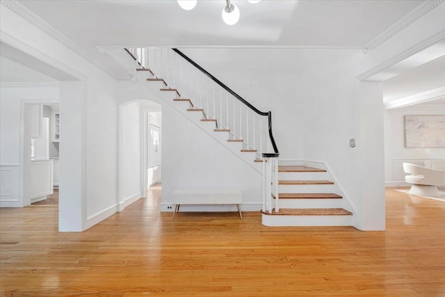 staircase with wood-type flooring and ornamental molding