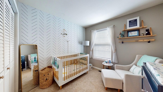 carpeted bedroom with an accent wall, baseboards, and a crib
