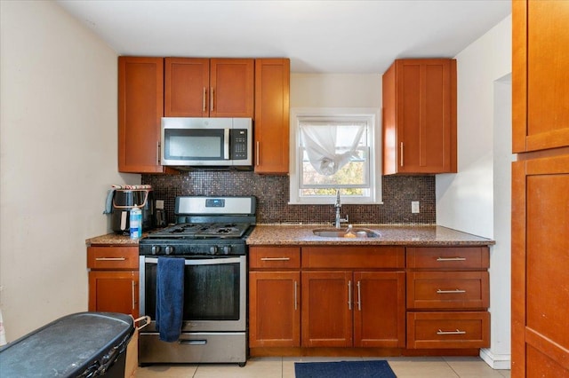 kitchen featuring stainless steel appliances, backsplash, a sink, and brown cabinets