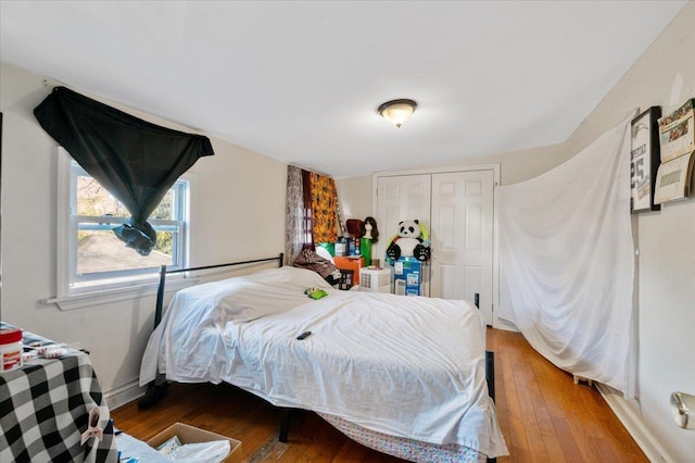 bedroom featuring a closet, wood-type flooring, and baseboards