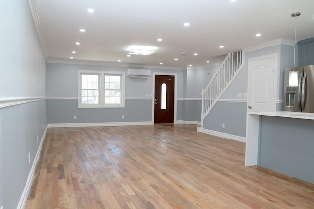 unfurnished living room with light hardwood / wood-style flooring, ornamental molding, and an AC wall unit