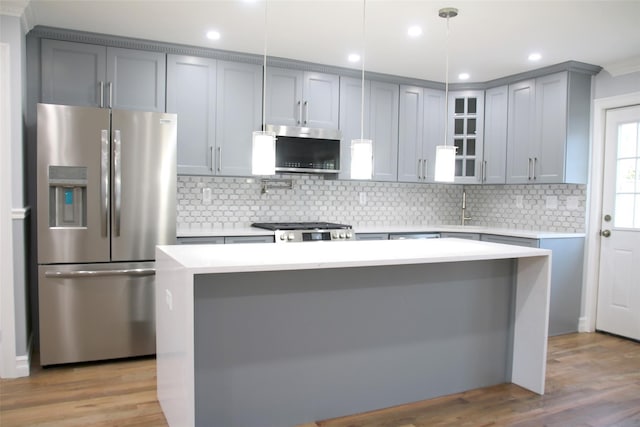 kitchen with stainless steel appliances, hanging light fixtures, light hardwood / wood-style floors, and decorative backsplash