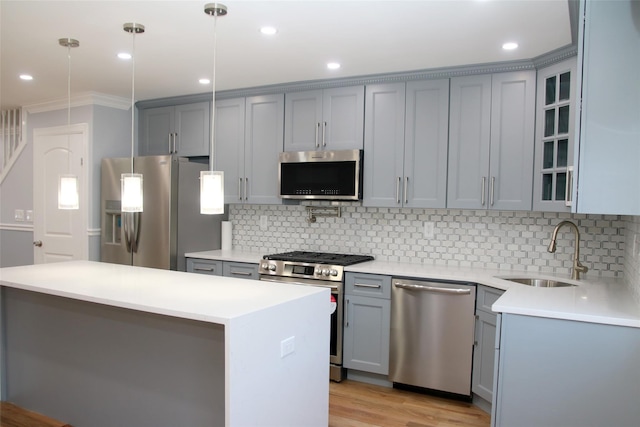 kitchen featuring sink, decorative light fixtures, a center island, light wood-type flooring, and stainless steel appliances