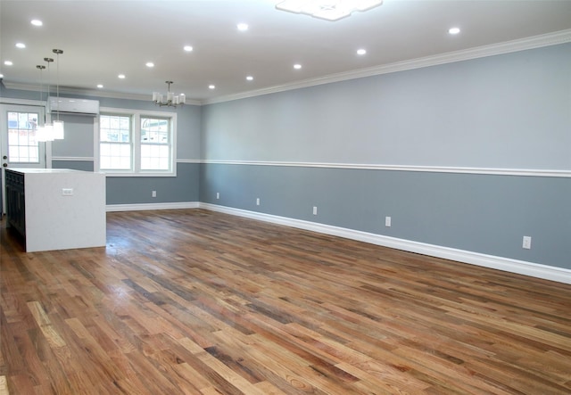 unfurnished living room with crown molding, a wall mounted air conditioner, dark hardwood / wood-style flooring, and a chandelier