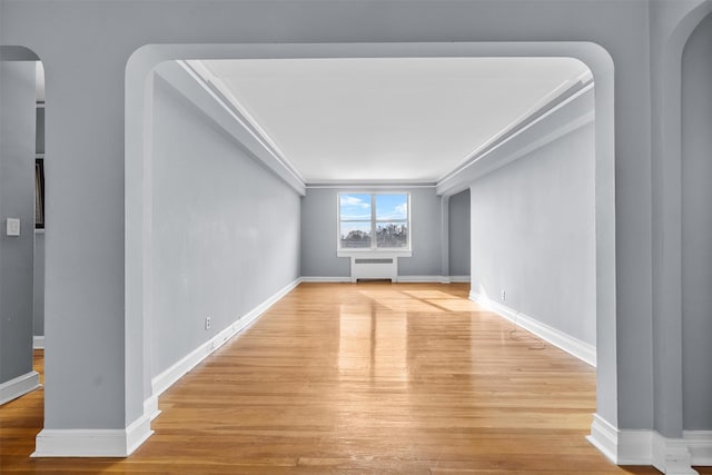 unfurnished living room featuring ornamental molding, radiator, and light wood-type flooring