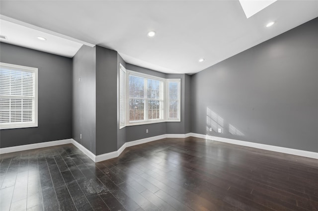 empty room featuring dark hardwood / wood-style floors and a skylight