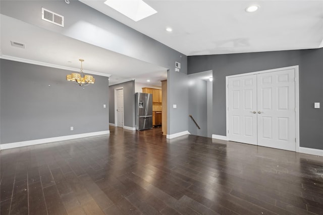 unfurnished living room featuring a notable chandelier, crown molding, lofted ceiling with skylight, and dark hardwood / wood-style floors