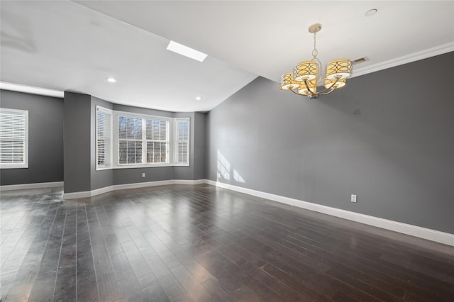 unfurnished room featuring plenty of natural light, dark hardwood / wood-style floors, vaulted ceiling with skylight, and a notable chandelier