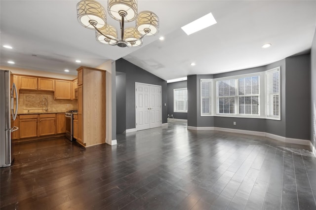 unfurnished living room featuring dark hardwood / wood-style floors, a chandelier, and vaulted ceiling with skylight