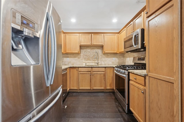 kitchen featuring sink, dark wood-type flooring, appliances with stainless steel finishes, backsplash, and light stone countertops