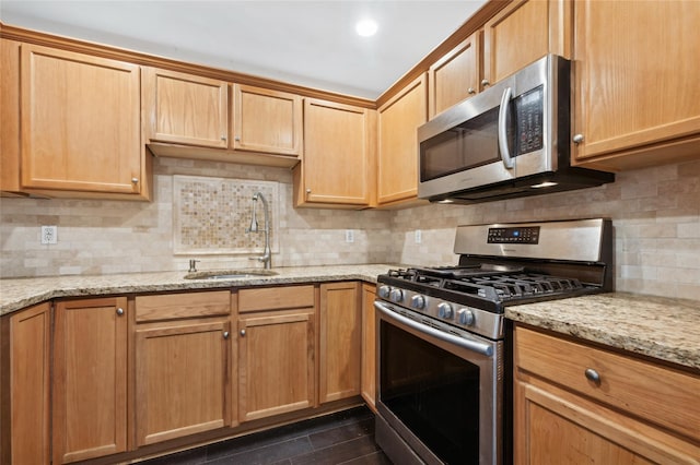 kitchen with appliances with stainless steel finishes, light stone countertops, sink, and decorative backsplash