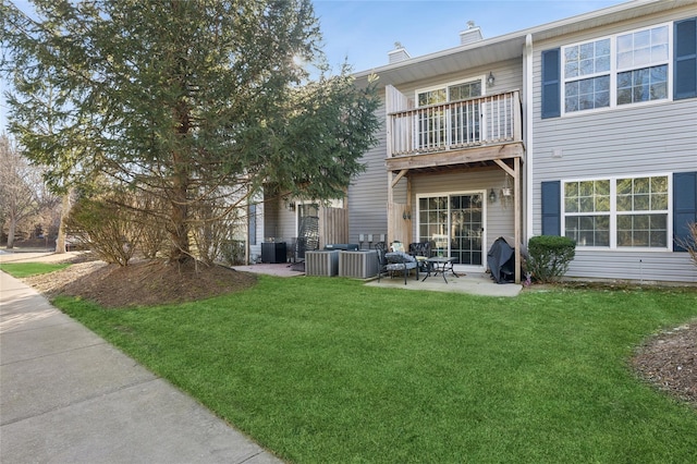 rear view of property featuring a balcony, a yard, central AC unit, and a patio