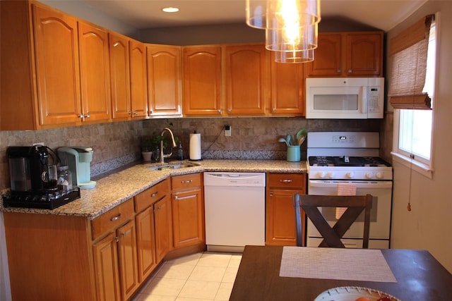 kitchen with pendant lighting, sink, white appliances, tasteful backsplash, and light stone counters